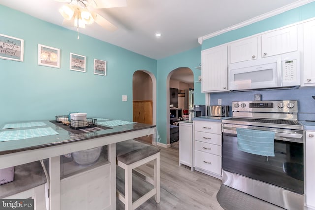 46 Jefferson St, Weatherly, PA 18255 - kitchen featuring white microwave, stainless steel range with electric stovetop, arched walkways, a ceiling fan, and light wood-style floors