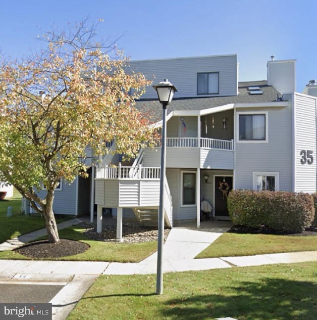view of property with a front lawn and a balcony