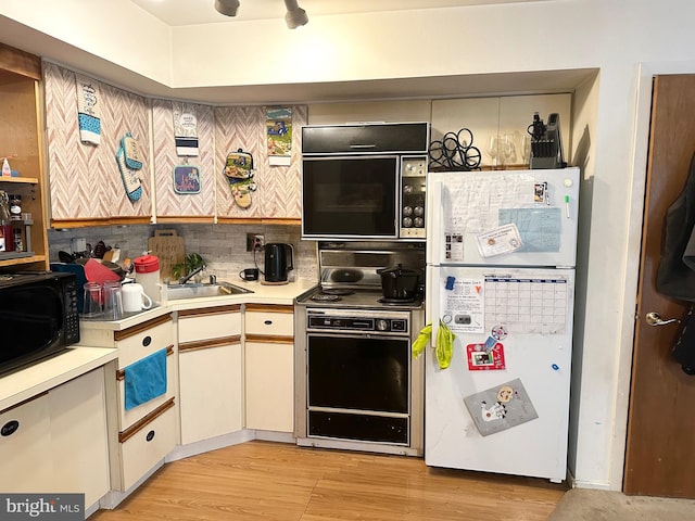 kitchen featuring freestanding refrigerator, range with electric stovetop, black microwave, and a sink