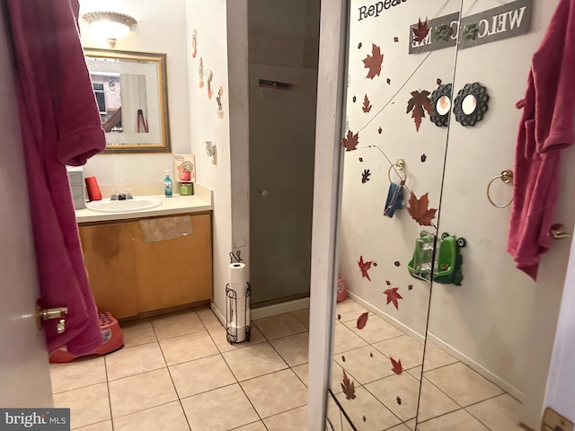 full bath with tile patterned flooring, vanity, a stall shower, and baseboards