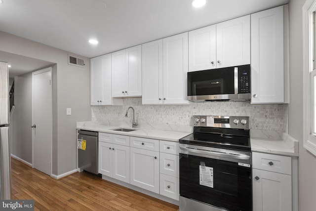 941 Sherwood Ct, Sterling, VA 20164 - kitchen featuring stainless steel appliances, a sink, light wood-style floors, white cabinets, and recessed lighting
