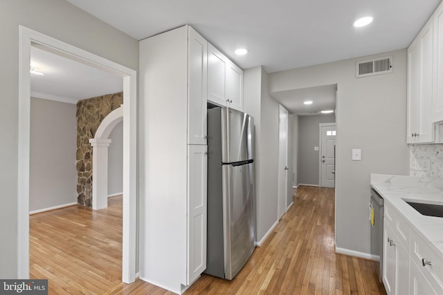 941 Sherwood Ct, Sterling, VA 20164 - kitchen with stainless steel appliances, light wood-style floors, white cabinets, arched walkways, and light stone countertops
