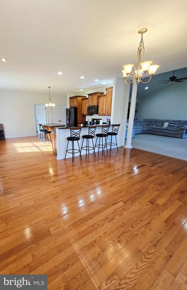 7677 Green Ridge Ln, Abbottstown, PA 17301 - kitchen with black appliances, a chandelier, open floor plan, a kitchen bar, and brown cabinetry