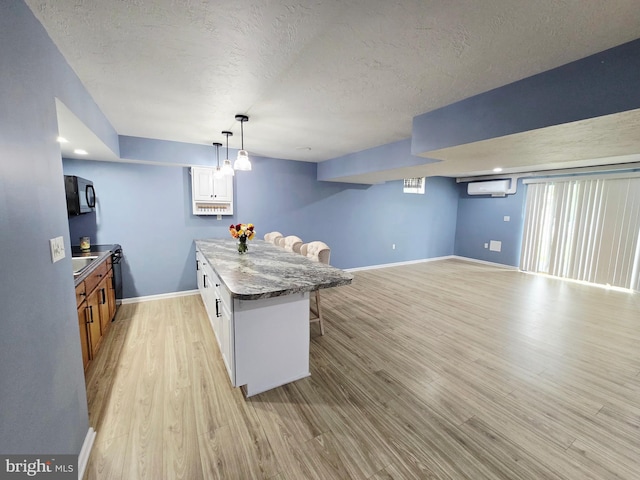 7677 Green Ridge Ln, Abbottstown, PA 17301 - kitchen with a breakfast bar area, black microwave, light wood-style flooring, a textured ceiling, and baseboards