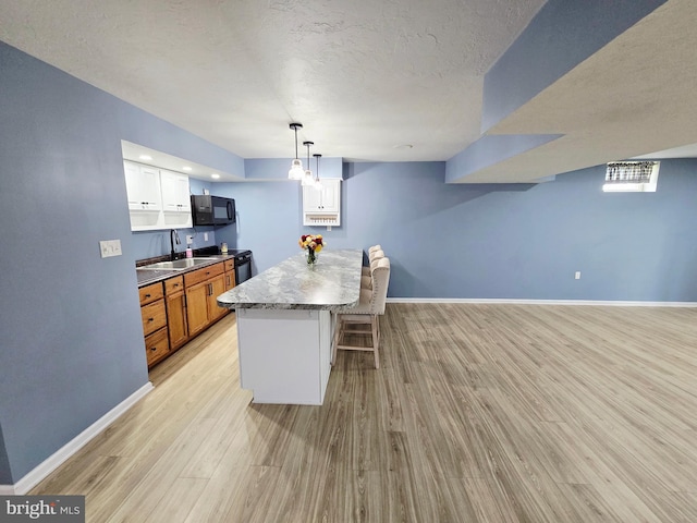 7677 Green Ridge Ln, Abbottstown, PA 17301 - kitchen with black appliances, a breakfast bar area, light wood-type flooring, baseboards, and a sink