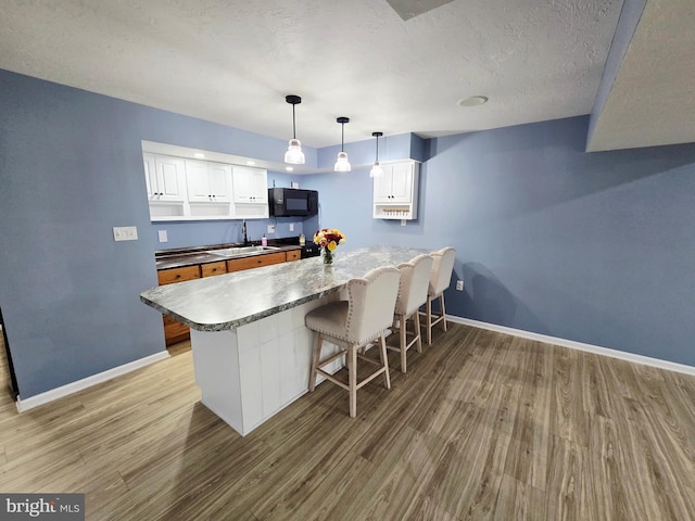 7677 Green Ridge Ln, Abbottstown, PA 17301 - kitchen with black microwave, a sink, baseboards, light wood-type flooring, and a textured ceiling