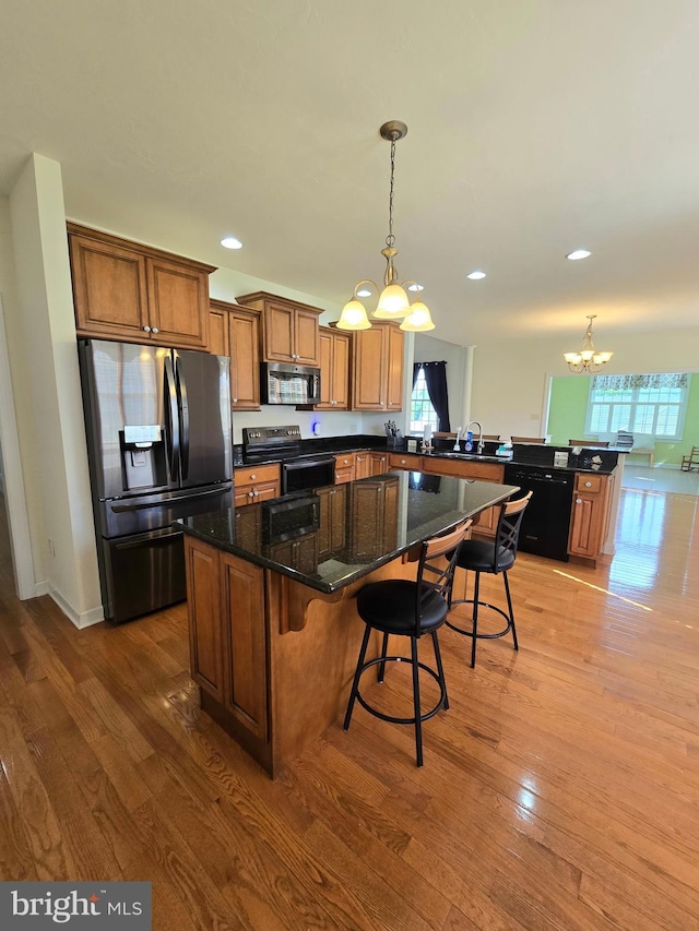 7677 Green Ridge Ln, Abbottstown, PA 17301 - kitchen with appliances with stainless steel finishes, a chandelier, a peninsula, wood finished floors, and brown cabinetry