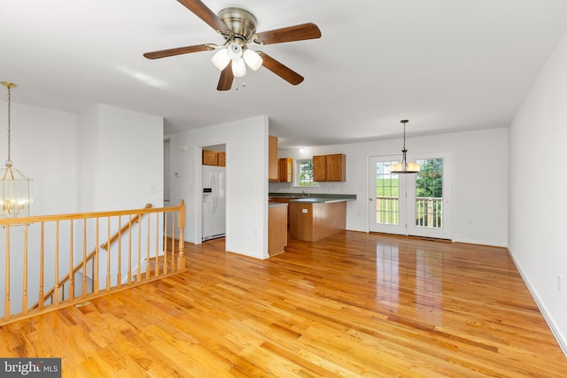 1118 Ashby St, Front Royal, VA 22630 - kitchen with white fridge with ice dispenser, light wood-style flooring, brown cabinets, dark countertops, and a chandelier