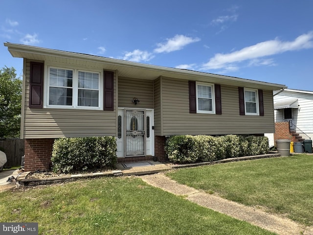 raised ranch featuring a front yard and brick siding