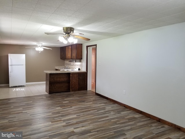 1320 Oak Ln, New Cumberland, PA 17070 - kitchen featuring freestanding refrigerator, a peninsula, wood finished floors, baseboards, and a ceiling fan