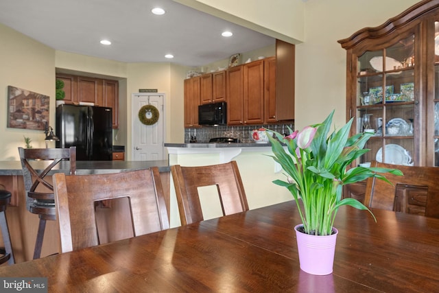 17365 Norland Way, Shrewsbury, PA 17361 - kitchen with black appliances, dark countertops, backsplash, brown cabinetry, and a kitchen breakfast bar