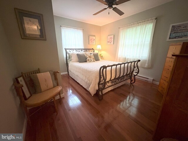 bedroom with wood finished floors, baseboards, a ceiling fan, and baseboard heating