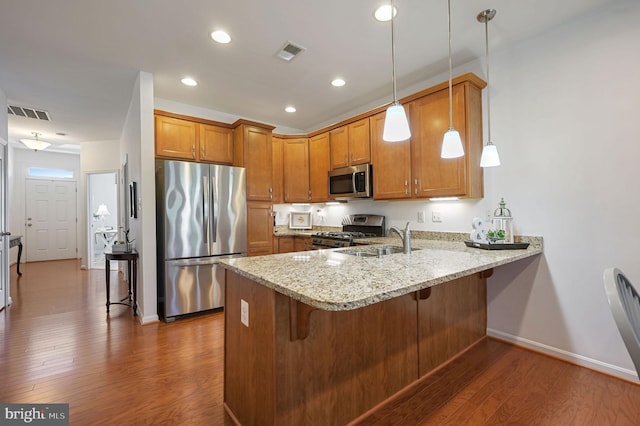 42 Cresthaven Ln, Dover, DE 19901 - kitchen with stainless steel appliances, brown cabinets, a peninsula, dark wood-style floors, and a sink