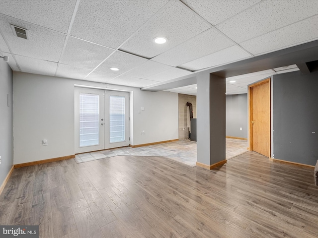 979 John Brown Farm Rd, Harpers Ferry, WV 25425 - empty room with baseboards, a drop ceiling, wood finished floors, a wood stove, and french doors
