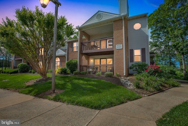 8822 Tanglewood Ln, Manassas, VA 20110 - view of front of house featuring a balcony, brick siding, a front yard, a chimney, and covered porch
