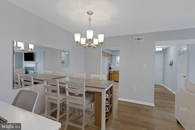 8822 Tanglewood Ln, Manassas, VA 20110 - dining room with a chandelier, light wood-type flooring, a fireplace, and baseboards