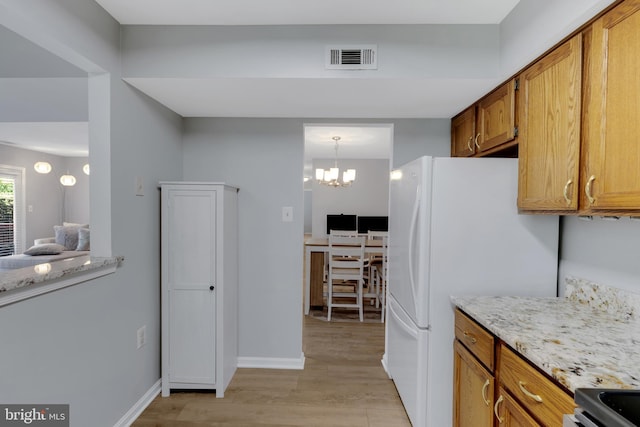 8822 Tanglewood Ln, Manassas, VA 20110 - kitchen featuring light wood-style floors, brown cabinetry, baseboards, a chandelier, and light stone counters