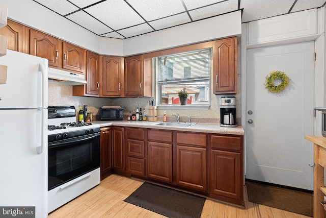 1409 S Clarion St, Philadelphia, PA 19147 - kitchen with white appliances, a sink, under cabinet range hood, light countertops, and light wood finished floors