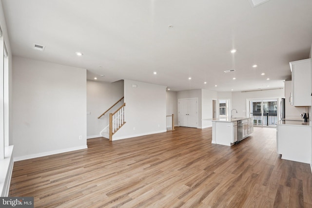 43730 Transit Sq, Ashburn, VA 20147 - unfurnished living room with recessed lighting, light wood-style flooring, a sink, baseboards, and stairs