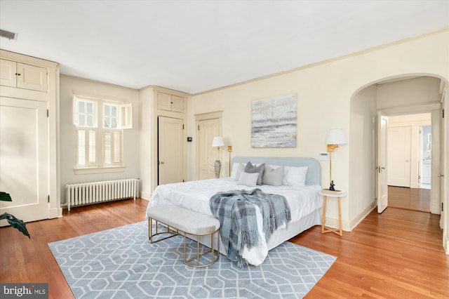 3419 Lowell St NW, Washington, DC 20016 - bedroom with radiator, arched walkways, and light wood finished floors