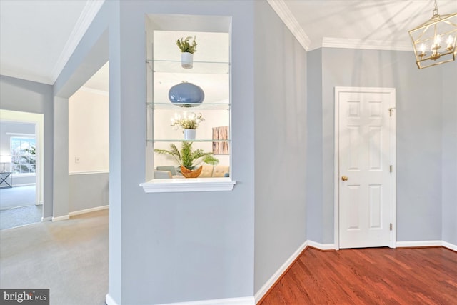 corridor with a chandelier, crown molding, baseboards, and wood finished floors