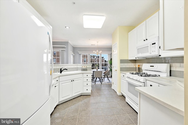 kitchen featuring white appliances, a chandelier, tasteful backsplash, a sink, and white cabinets