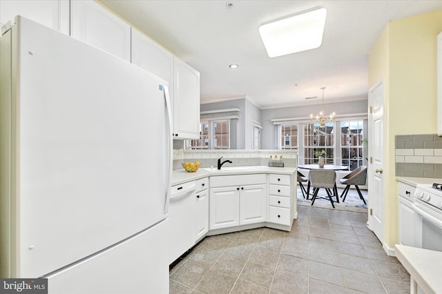 kitchen with white appliances, decorative backsplash, light countertops, a chandelier, and crown molding