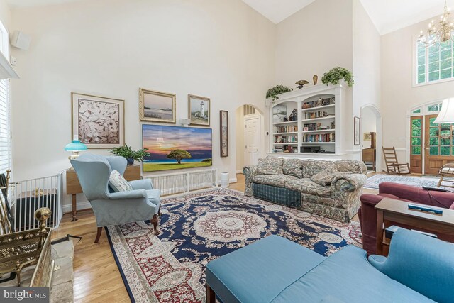 11709 Pine Tree Dr, Fairfax, VA 22033 - living room with arched walkways, high vaulted ceiling, wood finished floors, a chandelier, and baseboards