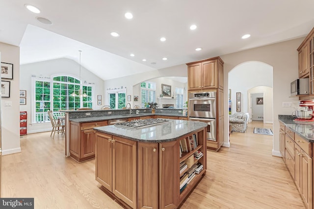 11709 Pine Tree Dr, Fairfax, VA 22033 - kitchen featuring arched walkways, appliances with stainless steel finishes, a center island, light wood finished floors, and vaulted ceiling
