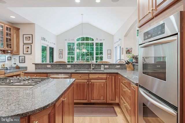11709 Pine Tree Dr, Fairfax, VA 22033 - kitchen featuring stainless steel appliances, a sink, brown cabinetry, dark stone countertops, and vaulted ceiling