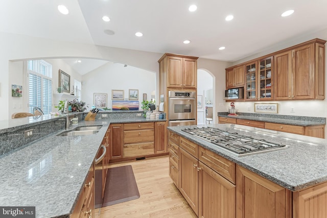 11709 Pine Tree Dr, Fairfax, VA 22033 - kitchen with arched walkways, appliances with stainless steel finishes, a sink, light wood-type flooring, and dark stone countertops