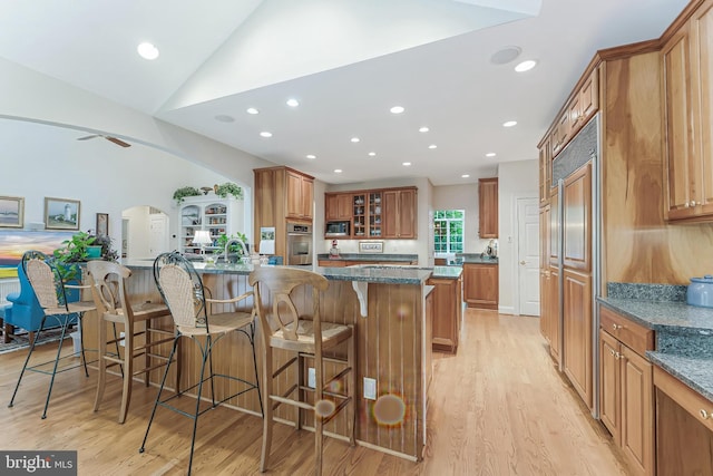 11709 Pine Tree Dr, Fairfax, VA 22033 - kitchen featuring appliances with stainless steel finishes, brown cabinetry, light wood-style floors, a kitchen bar, and recessed lighting
