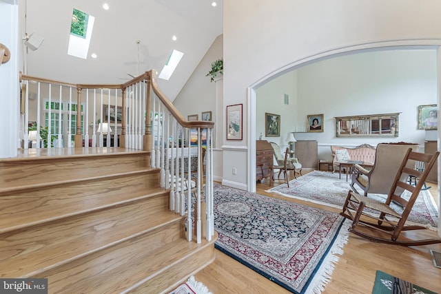 11709 Pine Tree Dr, Fairfax, VA 22033 - stairs with high vaulted ceiling, a skylight, wood finished floors, arched walkways, and recessed lighting