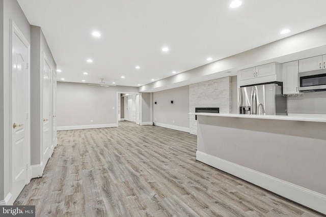 1473 Evans Farm Dr, Mclean, VA 22101 - unfurnished living room with light wood-style floors, recessed lighting, a stone fireplace, a ceiling fan, and baseboards