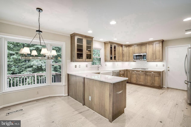 5926 Clermont Landing Ct, Burke, VA 22015 - kitchen featuring appliances with stainless steel finishes, a peninsula, brown cabinetry, a sink, and decorative backsplash