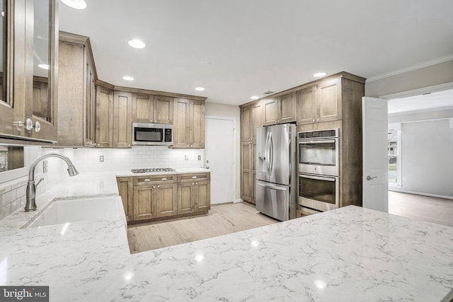 5926 Clermont Landing Ct, Burke, VA 22015 - kitchen with appliances with stainless steel finishes, a sink, light stone counters, backsplash, and light wood-style floors