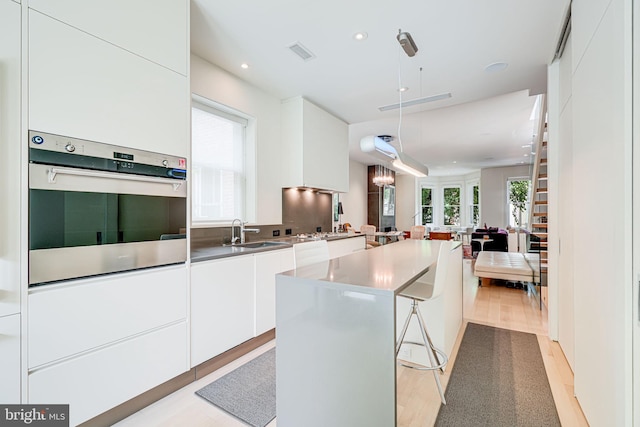 1448 Corcoran St NW, Washington, DC 20009 - kitchen featuring stainless steel oven, a sink, modern cabinets, white cabinets, and open floor plan