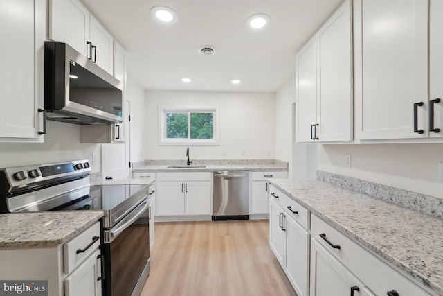 818 Dale Rd, Glen Burnie, MD 21060 - kitchen with stainless steel appliances, white cabinetry, a sink, light wood-style floors, and light stone counters
