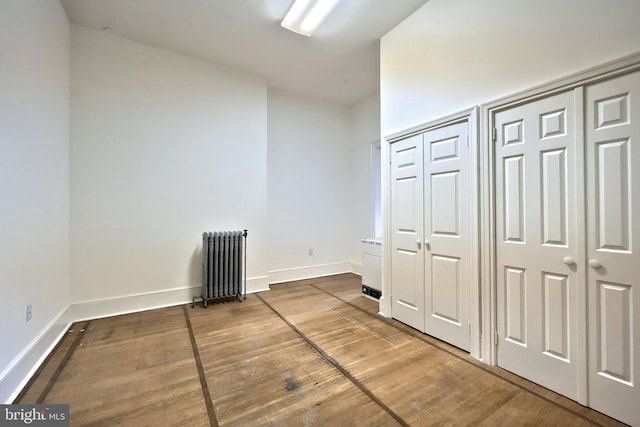 476 W Market St, York, PA 17401 - unfurnished bedroom featuring radiator heating unit, wood finished floors, baseboards, and two closets
