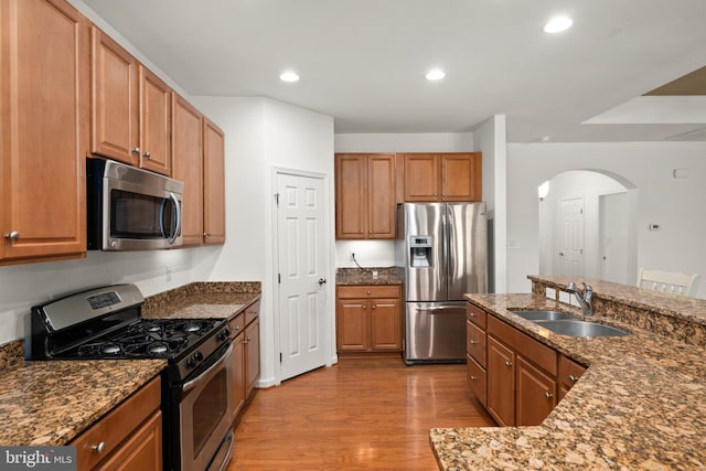 54 Ruddy Duck Ln, Bridgeville, DE 19933 - kitchen with appliances with stainless steel finishes, a sink, arched walkways, wood finished floors, and dark stone counters