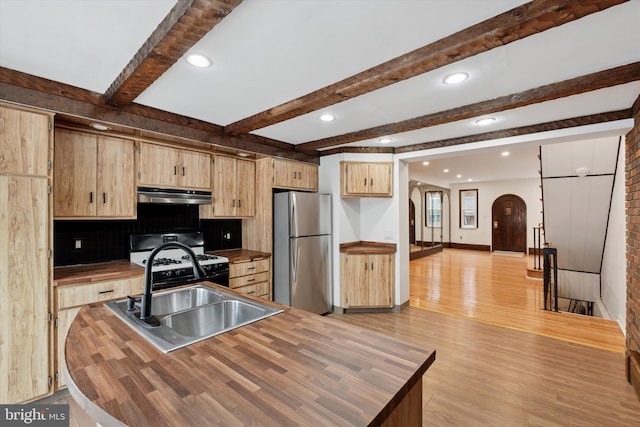 1142 Tree St, Philadelphia, PA 19148 - kitchen featuring wooden counters, freestanding refrigerator, under cabinet range hood, range with gas cooktop, and arched walkways