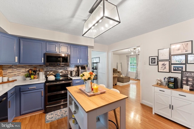 308 Fawn Dr, Winchester, VA 22602 - kitchen with appliances with stainless steel finishes, blue cabinetry, decorative backsplash, light wood finished floors, and a textured ceiling