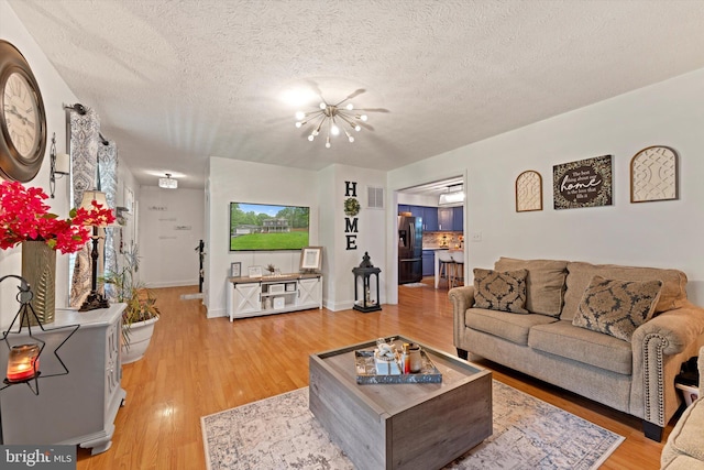 308 Fawn Dr, Winchester, VA 22602 - living room featuring a chandelier, light wood-type flooring, a textured ceiling, and baseboards