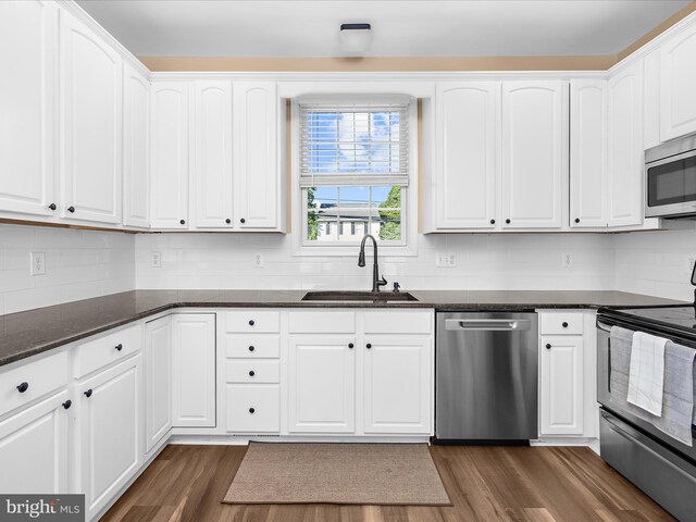 7827 Catherine Ave, Pasadena, MD 21122 - kitchen with stainless steel appliances, dark wood-style floors, white cabinetry, and backsplash