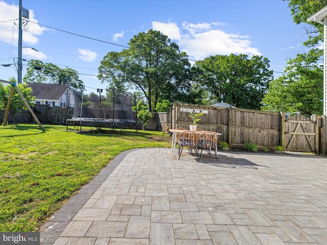 7827 Catherine Ave, Pasadena, MD 21122 - fenced backyard with a patio area, a trampoline, outdoor dining space, and a gate