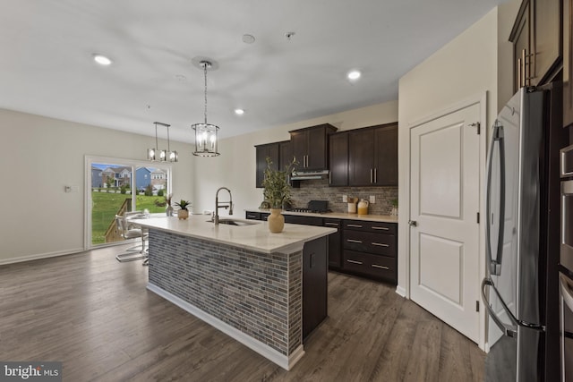 kitchen with a sink, freestanding refrigerator, gas stovetop, dark brown cabinetry, and dark wood finished floors