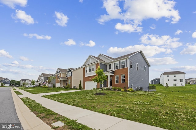 townhome / multi-family property featuring a residential view, a garage, brick siding, a front yard, and driveway