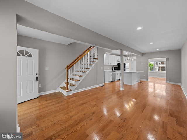 519 23rd Pl NE, Washington, DC 20002 - unfurnished living room with stairs, light wood-style floors, baseboards, recessed lighting, and a chandelier