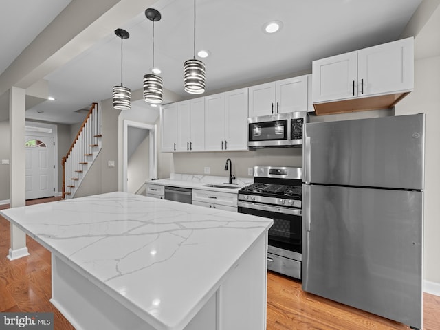 519 23rd Pl NE, Washington, DC 20002 - kitchen featuring stainless steel appliances, a sink, white cabinetry, light wood-style floors, and light stone countertops