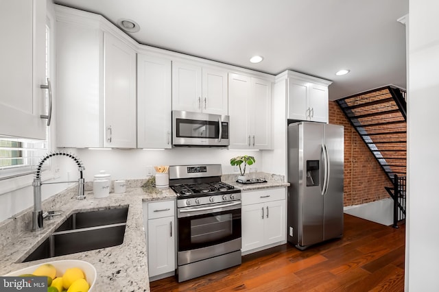 214 S Madeira St S, Baltimore, MD 21231 - kitchen with stainless steel appliances, a sink, brick wall, dark wood-type flooring, and white cabinetry